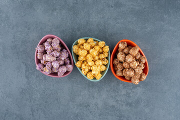 A variety of popcorn candy colors assorted in small bowls on marble background