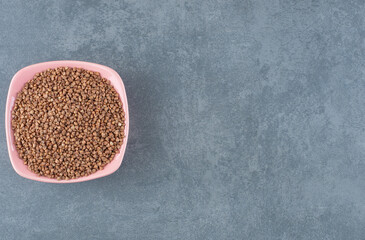 A bowl of raw buckwheat on marble background