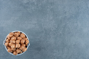 Brown popcorn candy filled into a small bucket on marble background