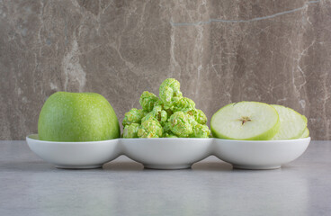 Serving platter of apples and popcorn candy on marble background