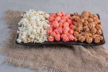 Platter full of popcorn and candied popcorn on a piece of cloth marble background