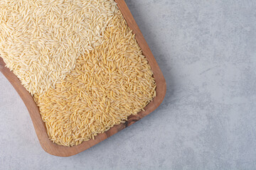 Wheat and rice heaped on a board on marble background