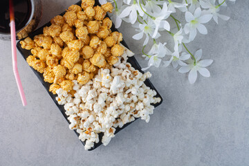 Flowers next to a glass of cola and a platter of popcorn on marble background