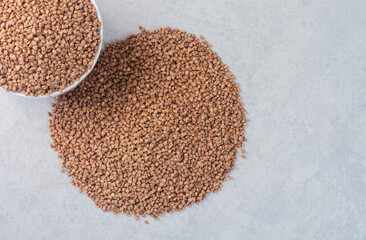 Buckwheat piled in a bowl and on marble background