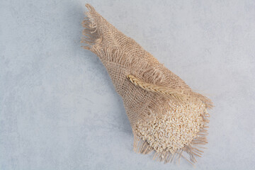 A small pile of wheat grain wrapped in a piece of cloth on marble background