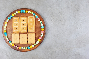 Biscuits encircled with popcorn candy on a wooden tray on marble background