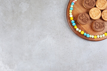 Tart cookies ringed with popcorn candies on a wooden tray on marble background