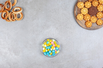 Obraz na płótnie Canvas Tied ring of sushki, a small bowl of popcorn candy and a tray of cookies on marble background