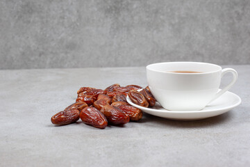 A number of dates next to a cup of tea on marble background