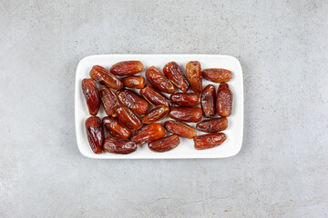 Square plate full of dates on marble background