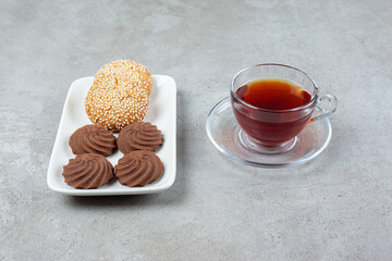A plate of different cookies and a cup of fragrant tea on marble background