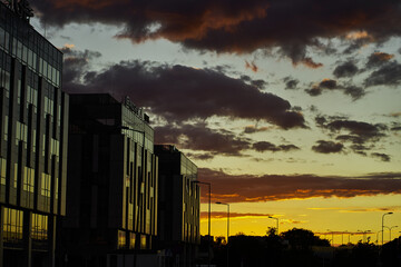 Zachód słońca odbity w szybach bloków miasto niebo chmury krajobraz cityscape