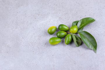 Handful of kumquats and leaves on on marble background