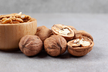Whole and cracked walnuts in on marble background