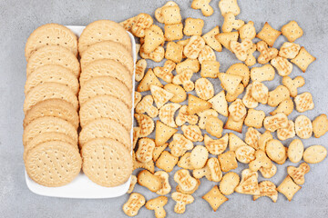 Biscuits lined up on a plate next to scattered biscuit chips on marble background