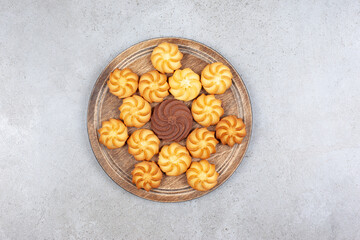 A decorative arrangement of cookies on wooden board on marble background