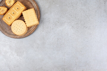 Assortment of various delectable biscuits on wooden board on marble background