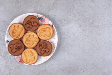 Tart cookies on decorated plate on marble background