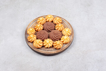 Cookies decoratively aligned on wooden board on marble background