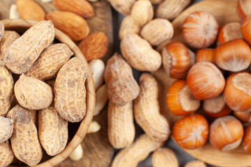 A heap of almonds, peanuts and hazelnuts in bowls and on wooden board