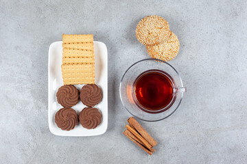 A cup of tea surrounded by an assortment of cookies