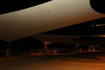 A parking structure area with large sun sail shades at night. - Powered by Adobe