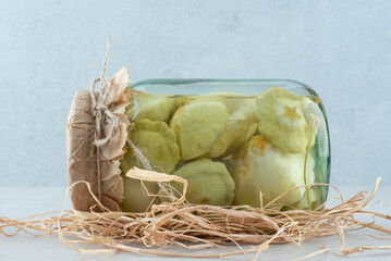 A jar of pickled vegetables on blue background