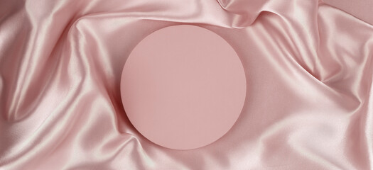 Geometric round platform podium on pale pink silk satin background. Blank minimal cylinder form...