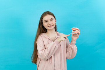 Front view of a young long-haired Caucasian teenage girl standing holding a toothbrush and a dental...