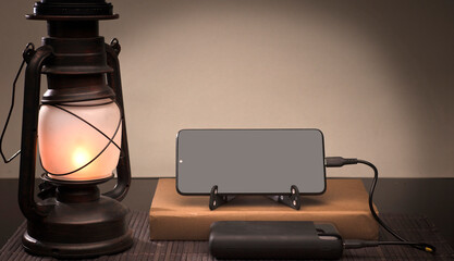 Smartphone with copy space, over book and oil lamp, social problem energy poverty.