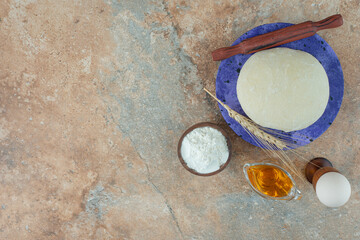 Dough with rolling pin and egg on marble background