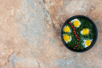 Obraz na płótnie Canvas Top view of dark pan with omelet and greens