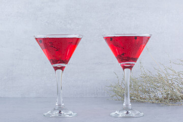 Two glasses of red juice on stone background