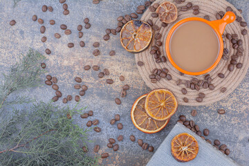 Cup of milk coffee with coffee beans and oranges