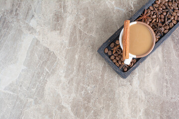 Cup of coffee and coffee beans on dark plate