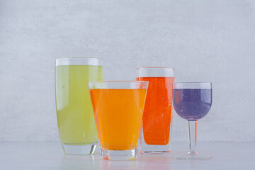 Four glasses of various juice on stone background