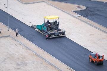 Asphalt paver laying asphalt road at construction site, car park reconstruction