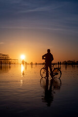 Silhouette of a person with a bike on low tide in Brighton 