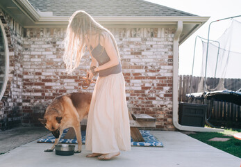 a woman feeding her German Shepherd dog outdoors in the backyard