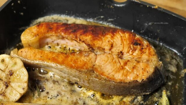 Fresh salmon steak is put on a hot grill pan for cooking.close-up