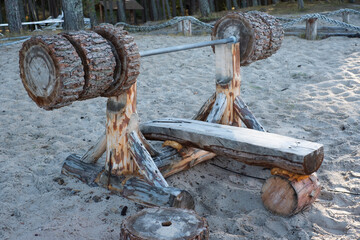 Wooden bench press equipment in a park made of heavy logs. Public outdoor gym in nature. 