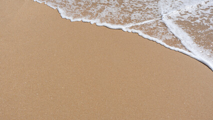 foam of the sea waves breaking on the beach shore