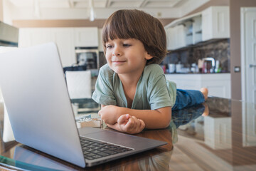 Cute. little boy using laptop in the livingroom with a cheerful smile