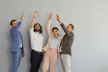 Team of happy excited people celebrating success. Group portrait of four confident coworkers, teammates and business partners standing in studio and giving each other high five. Teamwork concept
