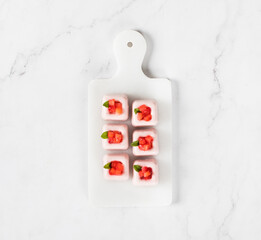 Strawberry cream dessert, Panna Cotta in the form of small square portions, on a serving board. White background. Top view