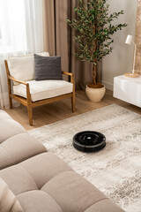 View of a robot vacuum cleaner working on a carpet in a new living room in light beige and gray...
