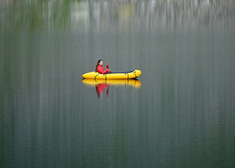 Woman in Packraft on Mountain Lake with Beautiful Reflection on Water