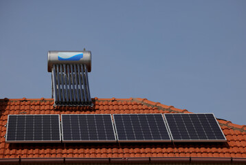 Solar panel  and vacuum air collectors for water heating on a red roof on a house.