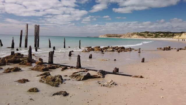 Left to right panning motion of the ruins and Pylons that Remain of the 1860s jetty on the beach at Port Willunga, south Australia, Australia