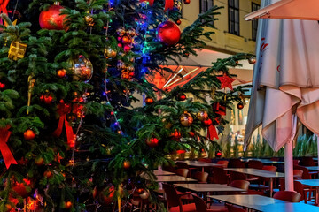 Branch of decorated Christmas tree in late evening on the street with night illumination.